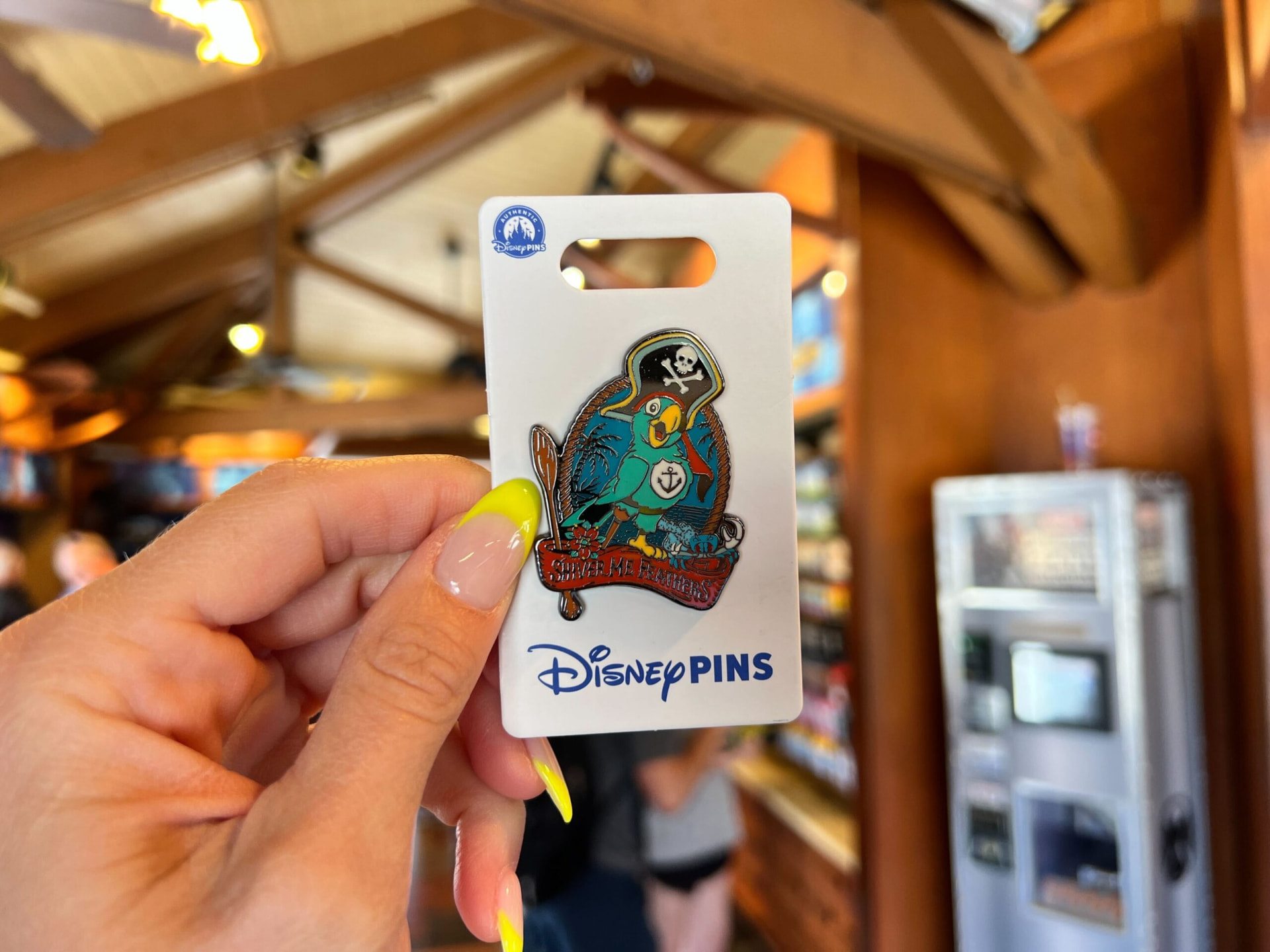 Collectible parrot trading pin held up inside a park pin shop