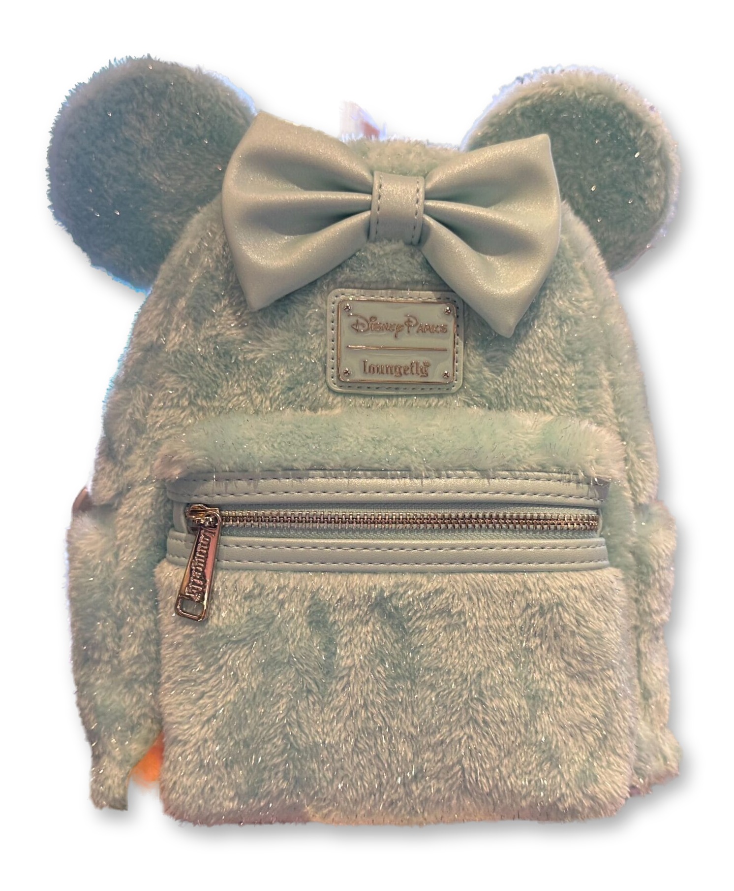 Hand holding an ice-blue fluffy Loungefly mini backpack with sparkly Minnie Mouse ears and a matching bow, in a Disney Parks store