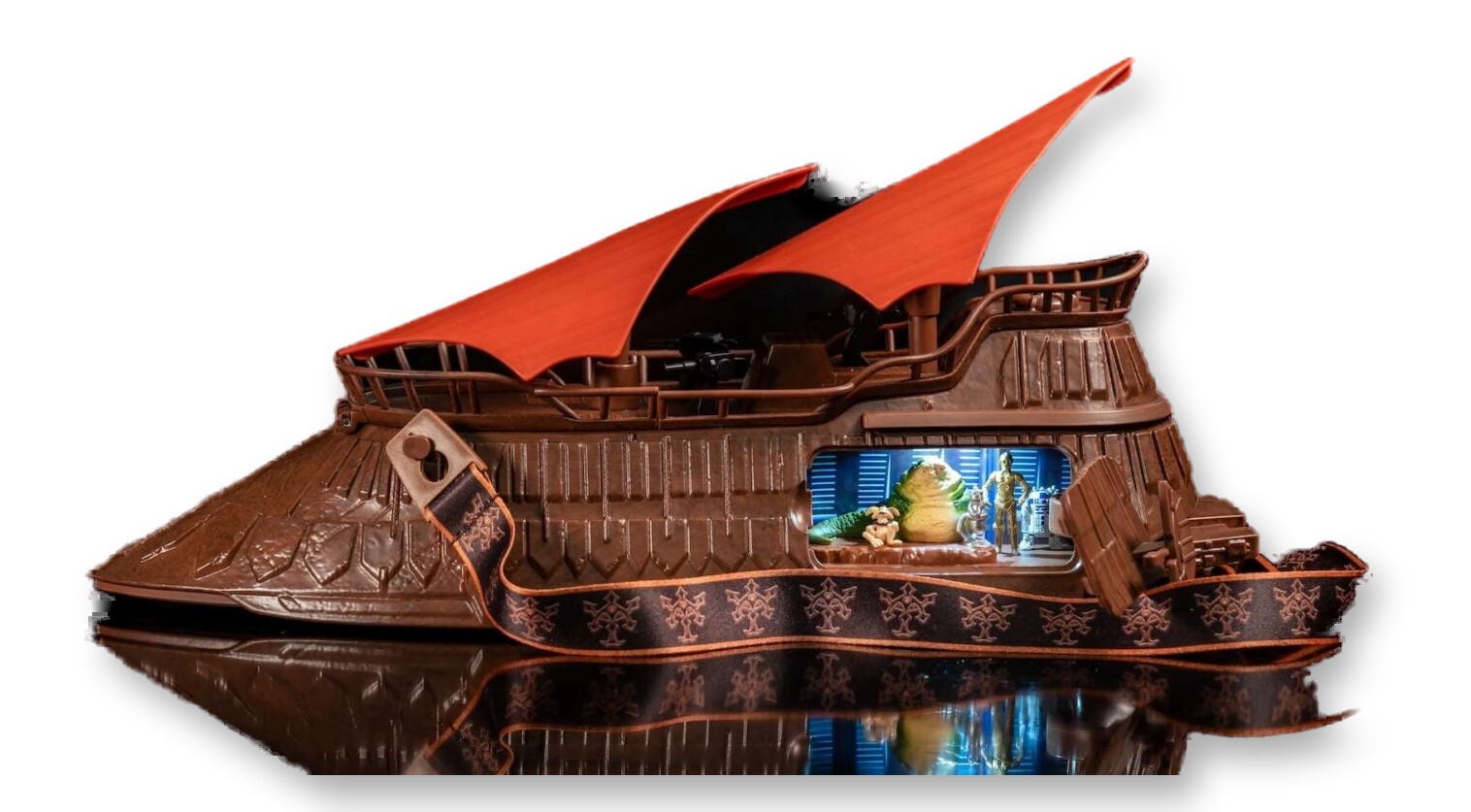 Brown popcorn bucket shaped like Jabba the Hutt's sail barge with two upswept orange sails, an open side hatch showing lit figures of Jabba, C-3PO, and R2-D2, and a decorative shoulder strap, photographed against a black background.