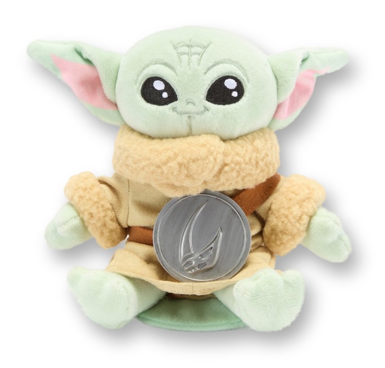 Small plush figure of Grogu (Baby Yoda) seated cross-legged wearing his brown robe, with a round silver magnetic disc positioned in front of him, photographed alone against a white background.