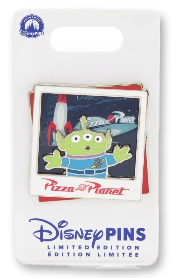 Enamel pin on its Disney Pins backing card styled as a stacked photo Polaroid showing the three-eyed green Alien toy in front of the Pizza Planet rocket, with a red 'Pizza Planet' logo plate below.