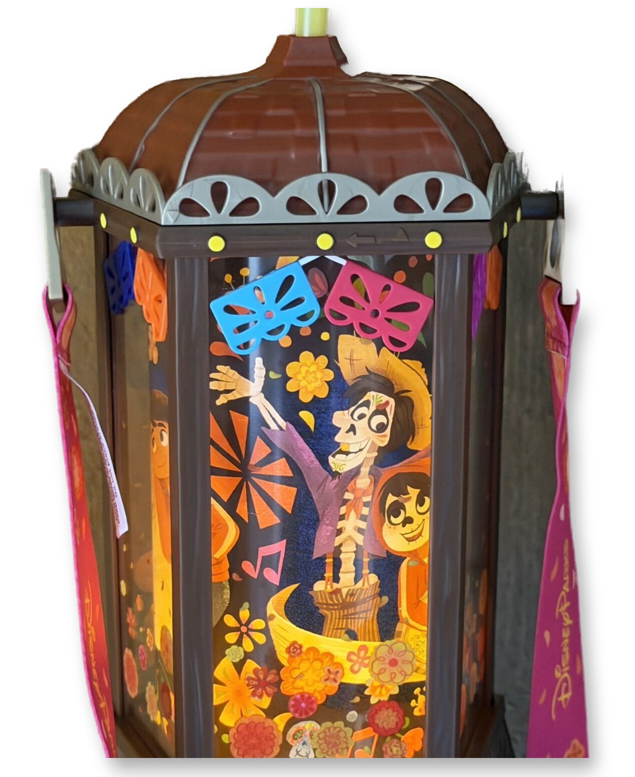 Illuminated hexagonal Coco-themed lantern sipper cup showing Miguel and Mama Coco artwork inside, with a yellow straw and pink lanyard